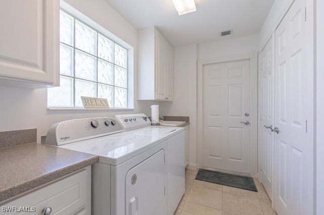 clothes washing area with light tile patterned flooring, cabinets, and washing machine and dryer