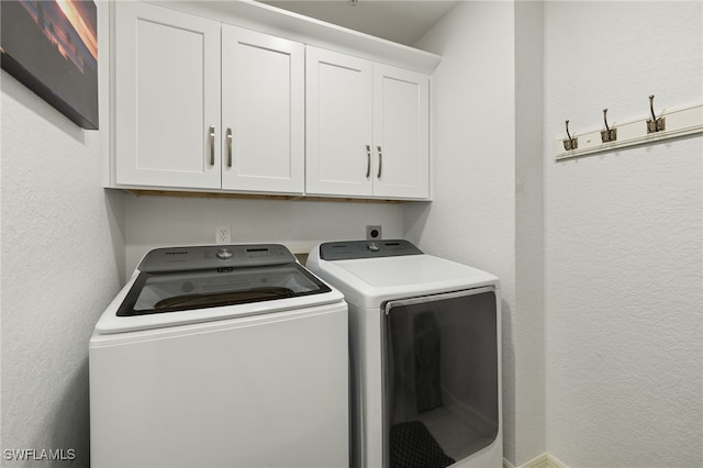 washroom with cabinets and washing machine and clothes dryer