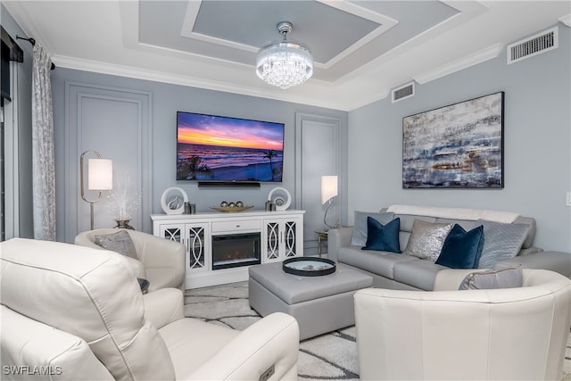 living room with a notable chandelier, a raised ceiling, and crown molding