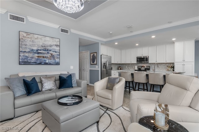 carpeted living room featuring a notable chandelier, ornamental molding, and sink