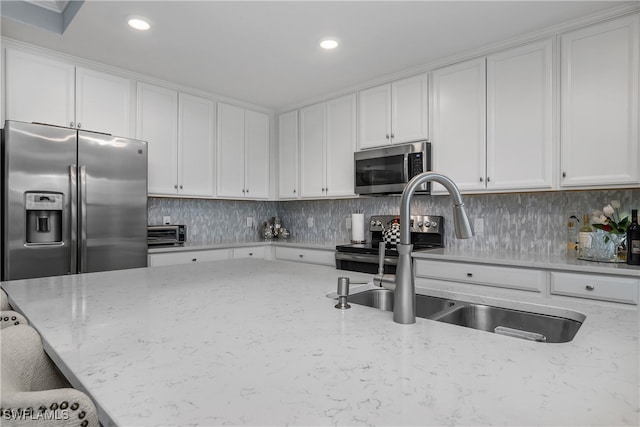 kitchen featuring light stone countertops, sink, decorative backsplash, white cabinets, and appliances with stainless steel finishes