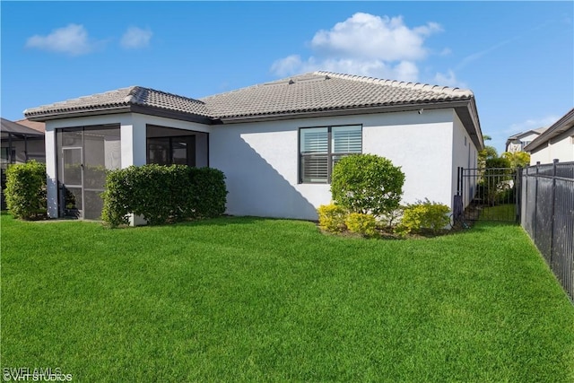 rear view of property featuring a sunroom and a lawn