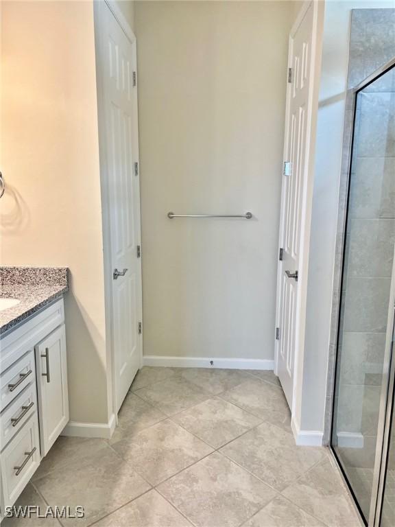 bathroom featuring tile patterned flooring, vanity, and a shower with shower door