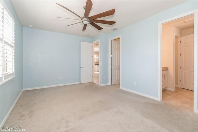 unfurnished bedroom featuring ceiling fan, connected bathroom, light colored carpet, and multiple windows