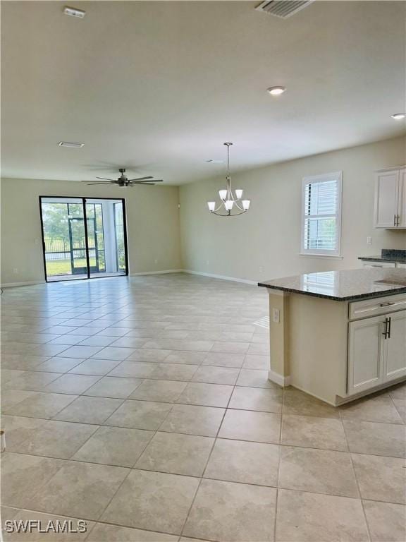 kitchen with dark stone countertops, decorative light fixtures, white cabinets, and light tile patterned flooring