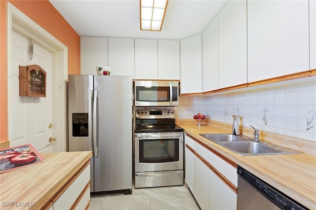 kitchen with light tile patterned floors, stainless steel appliances, white cabinetry, and sink