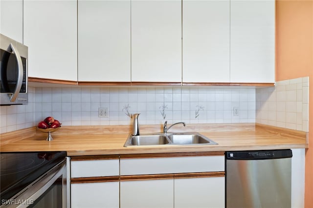 kitchen featuring stainless steel appliances, white cabinetry, tasteful backsplash, and sink