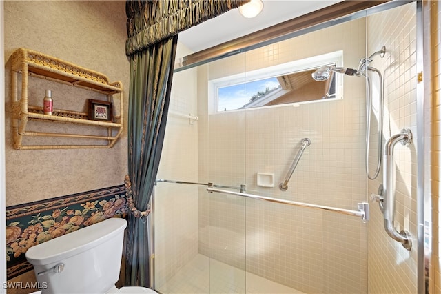 bathroom featuring toilet and a shower with shower door