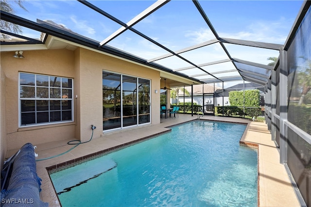 view of pool with glass enclosure and a patio area