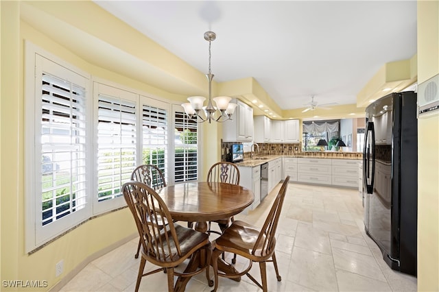 dining area with ceiling fan with notable chandelier and sink