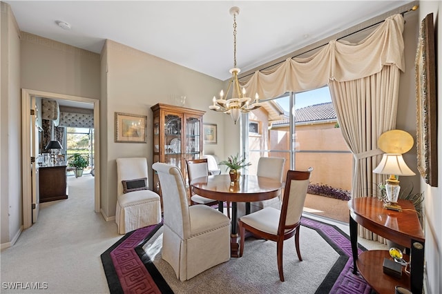 dining room featuring light carpet and a chandelier