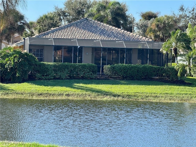 back of property with a lawn and a water view