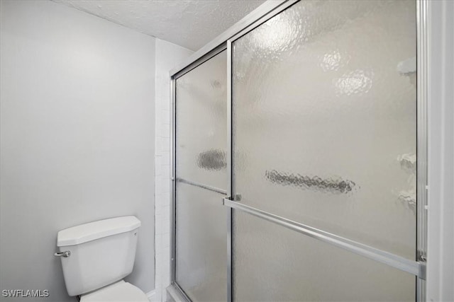 4231 SE 19th Pl Unit 1J, Cape Coral, FL 33904 - bathroom featuring toilet, a shower with door, and a textured ceiling