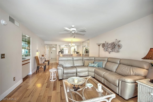 living room with light wood-type flooring and ceiling fan with notable chandelier