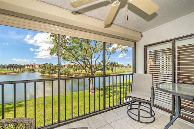 sunroom with ceiling fan and a water view