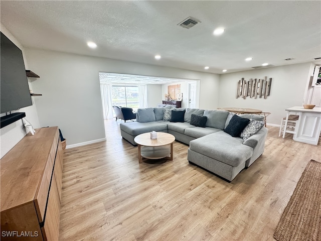 living room with a textured ceiling and light hardwood / wood-style flooring