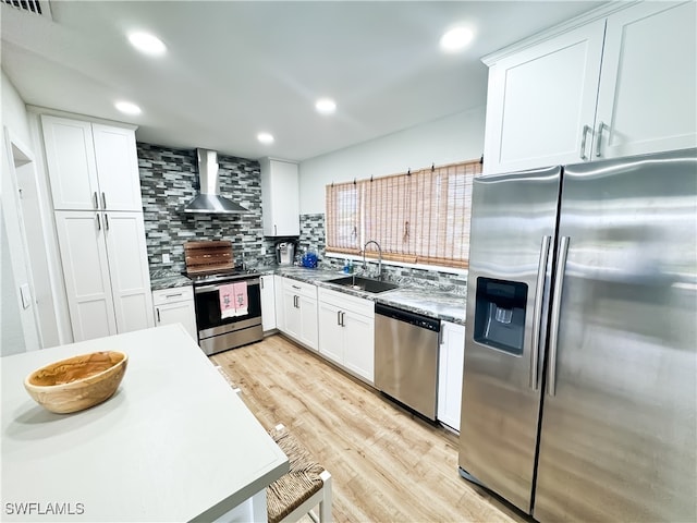 kitchen with white cabinets, stainless steel appliances, sink, and wall chimney range hood