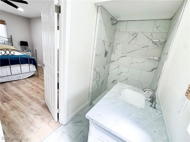 bathroom with ceiling fan, tiled shower, and vanity