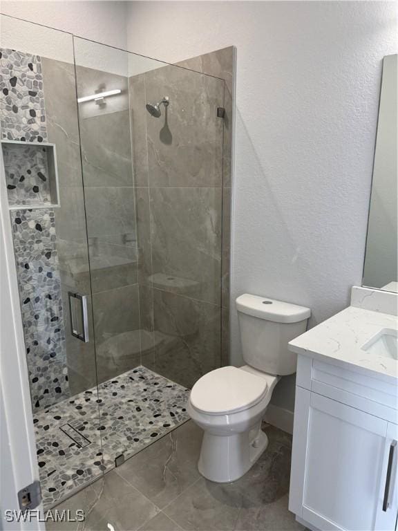 bathroom featuring vanity, a shower with shower door, and toilet