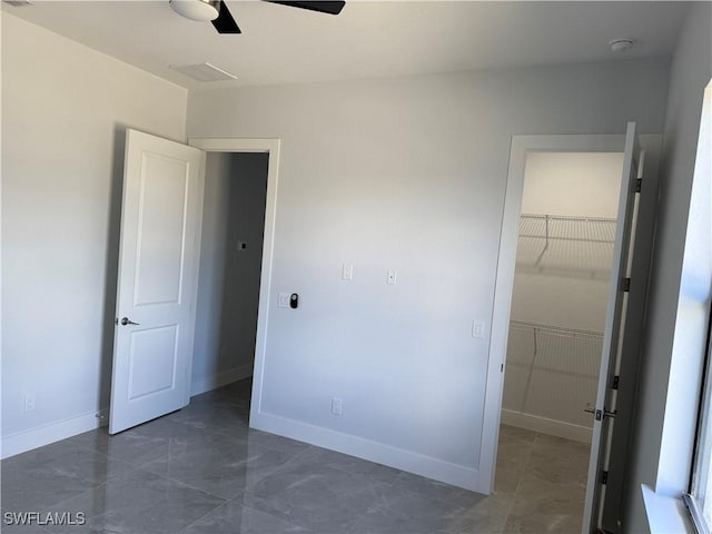 unfurnished bedroom with a spacious closet, a closet, and ceiling fan