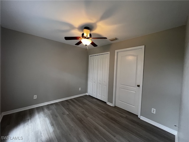 unfurnished bedroom with dark wood-type flooring, ceiling fan, and multiple closets