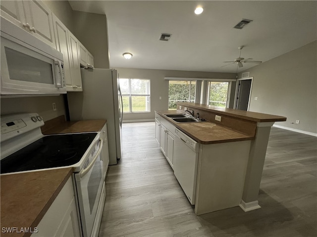 kitchen featuring sink, white appliances, a kitchen island with sink, and white cabinets