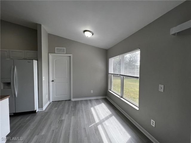 unfurnished dining area with hardwood / wood-style flooring and vaulted ceiling