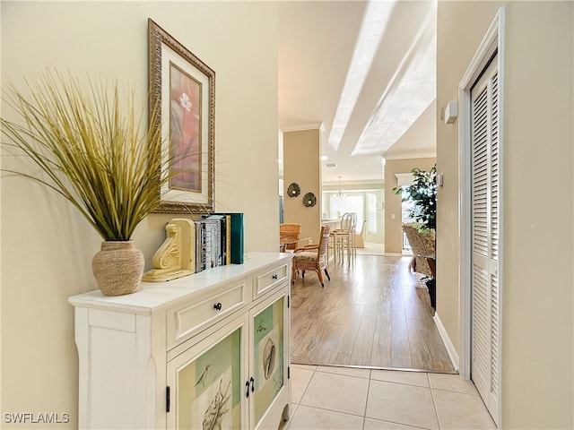 corridor with light hardwood / wood-style floors and ornamental molding