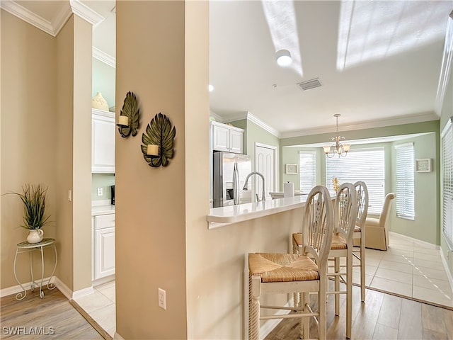 kitchen with white cabinets, light wood-type flooring, stainless steel fridge with ice dispenser, and ornamental molding