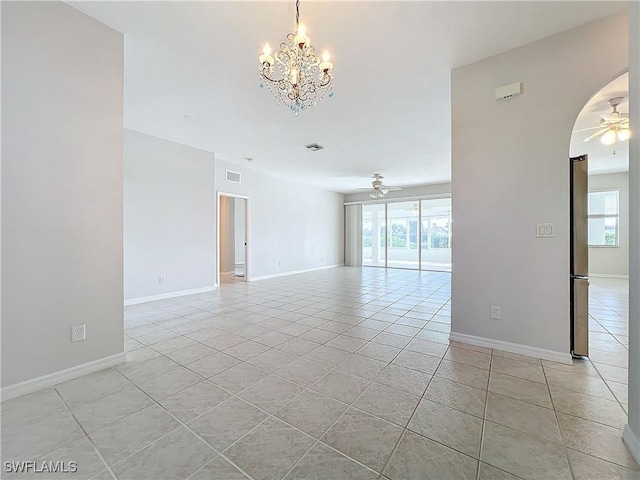 tiled spare room featuring ceiling fan with notable chandelier