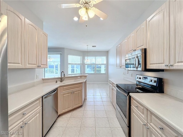 kitchen with sink, hanging light fixtures, ceiling fan, light tile patterned floors, and appliances with stainless steel finishes