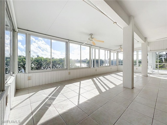 unfurnished sunroom featuring ceiling fan, plenty of natural light, and a water view