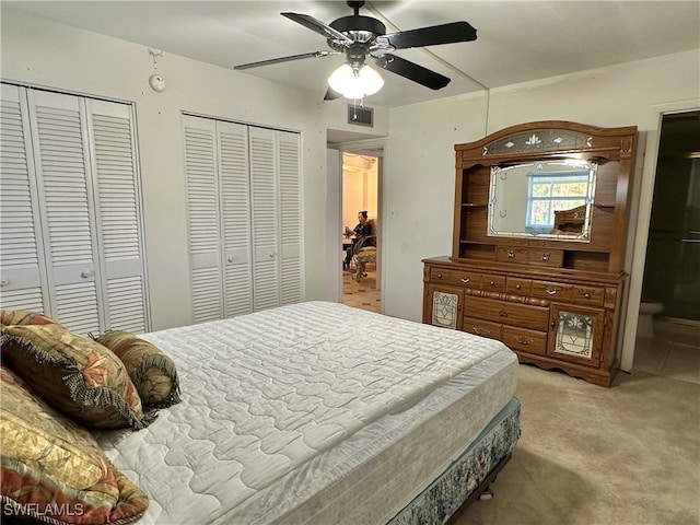 carpeted bedroom with two closets and ceiling fan