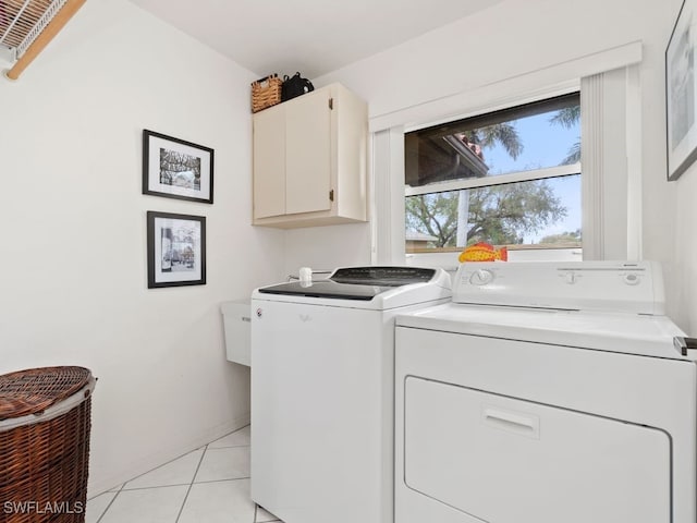 clothes washing area featuring cabinets, washer and dryer, and light tile patterned floors