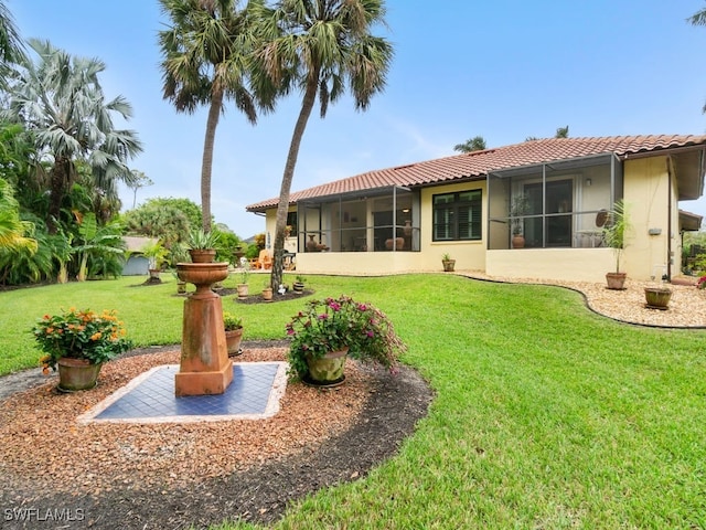 rear view of house featuring a sunroom and a lawn