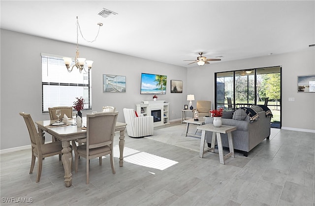 dining space featuring ceiling fan with notable chandelier, plenty of natural light, and light wood-type flooring