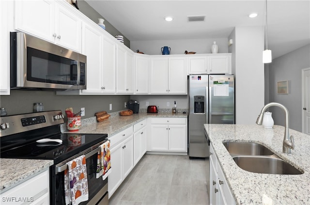 kitchen with stainless steel appliances, white cabinetry, sink, and pendant lighting