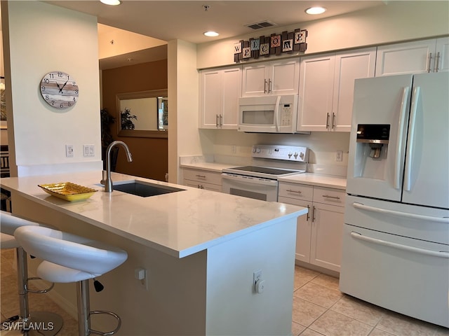 kitchen featuring white appliances, white cabinetry, sink, and light stone counters