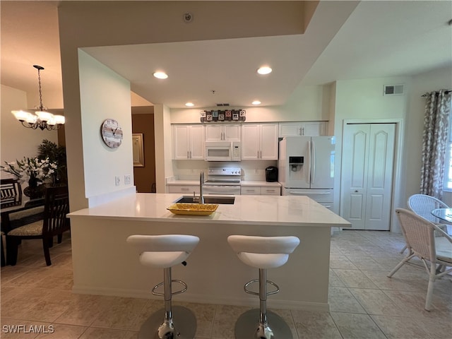 kitchen with a kitchen bar, stainless steel appliances, sink, a notable chandelier, and white cabinets