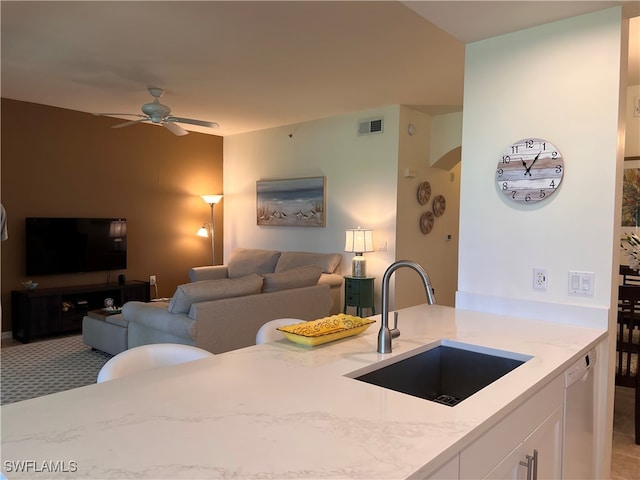 kitchen featuring light stone counters, white dishwasher, ceiling fan, sink, and white cabinets