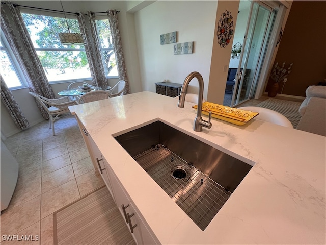 kitchen with white cabinets, light tile patterned floors, pendant lighting, and sink