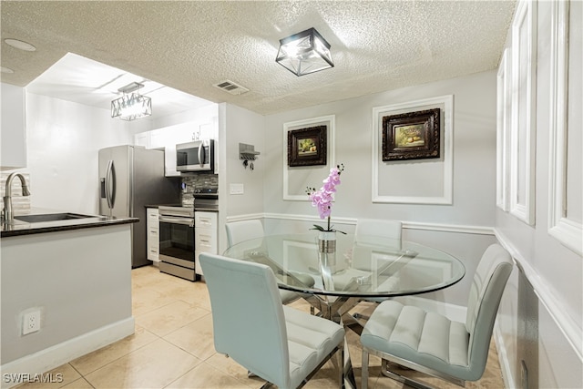 tiled dining room featuring a textured ceiling and sink