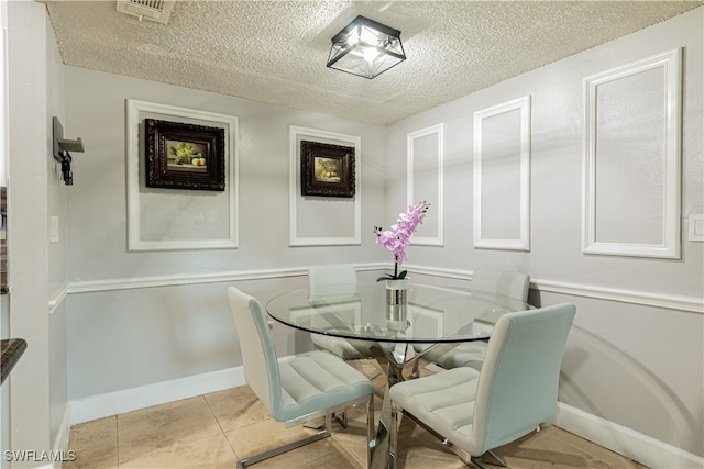 dining room featuring a textured ceiling and light tile patterned flooring