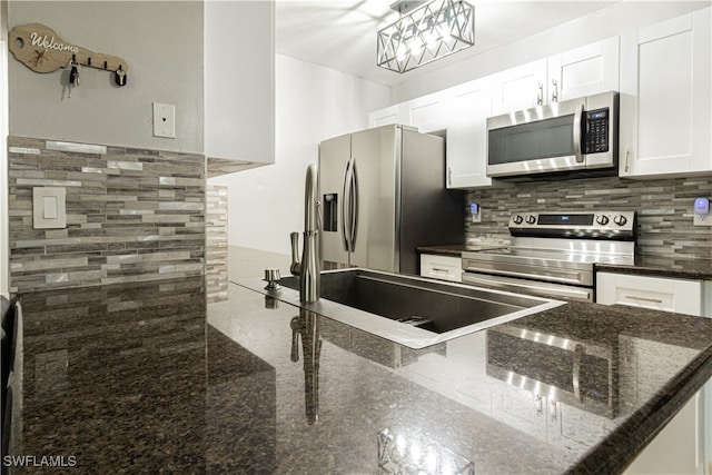 kitchen featuring tasteful backsplash, white cabinets, dark stone counters, and appliances with stainless steel finishes