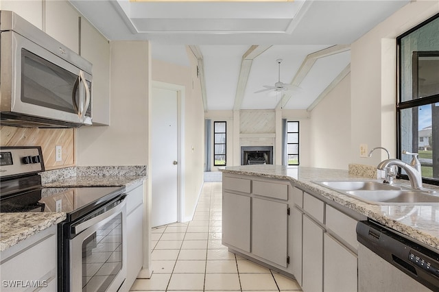 kitchen featuring vaulted ceiling with beams, appliances with stainless steel finishes, sink, and a healthy amount of sunlight