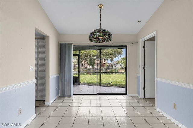 unfurnished dining area with light tile patterned floors and vaulted ceiling