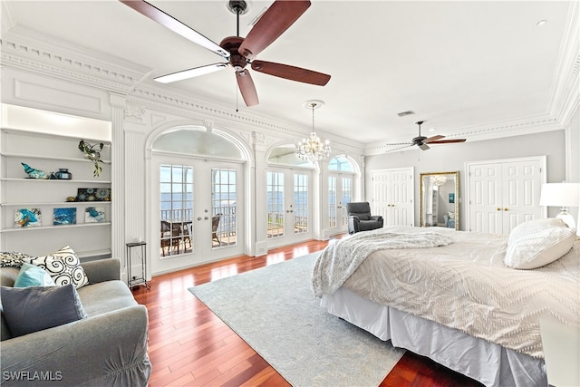 bedroom with hardwood / wood-style flooring, ceiling fan with notable chandelier, multiple windows, and french doors