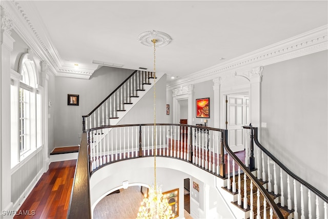 stairs with wood-type flooring, crown molding, and a notable chandelier