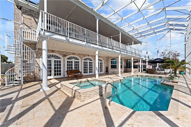 view of swimming pool with a patio area, french doors, a lanai, and an in ground hot tub