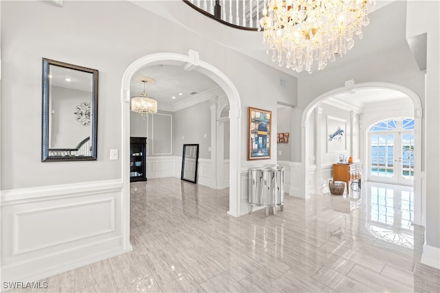 hall with crown molding, an inviting chandelier, and french doors